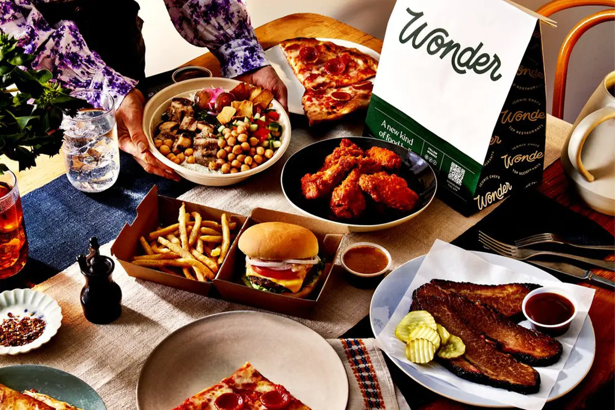 An assortment of food on a table with a to-go bag with Wonder written on it