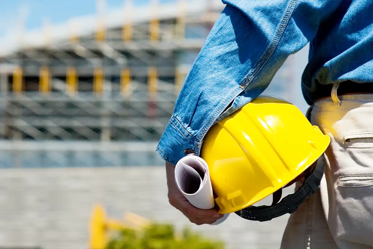 person holding a hard hat and construction plans