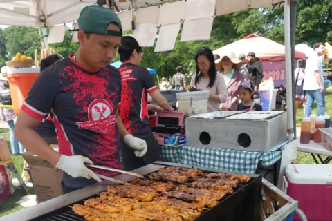 person cooking chicken on grill at International Food and Culture Festival