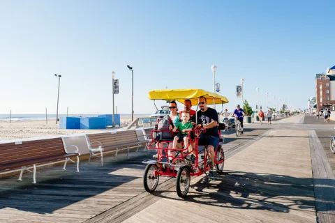 people riding pedal bike on ocean city boardwalk