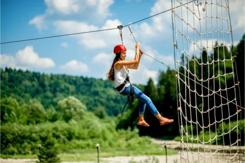 a woman ziplines on an outdoor course