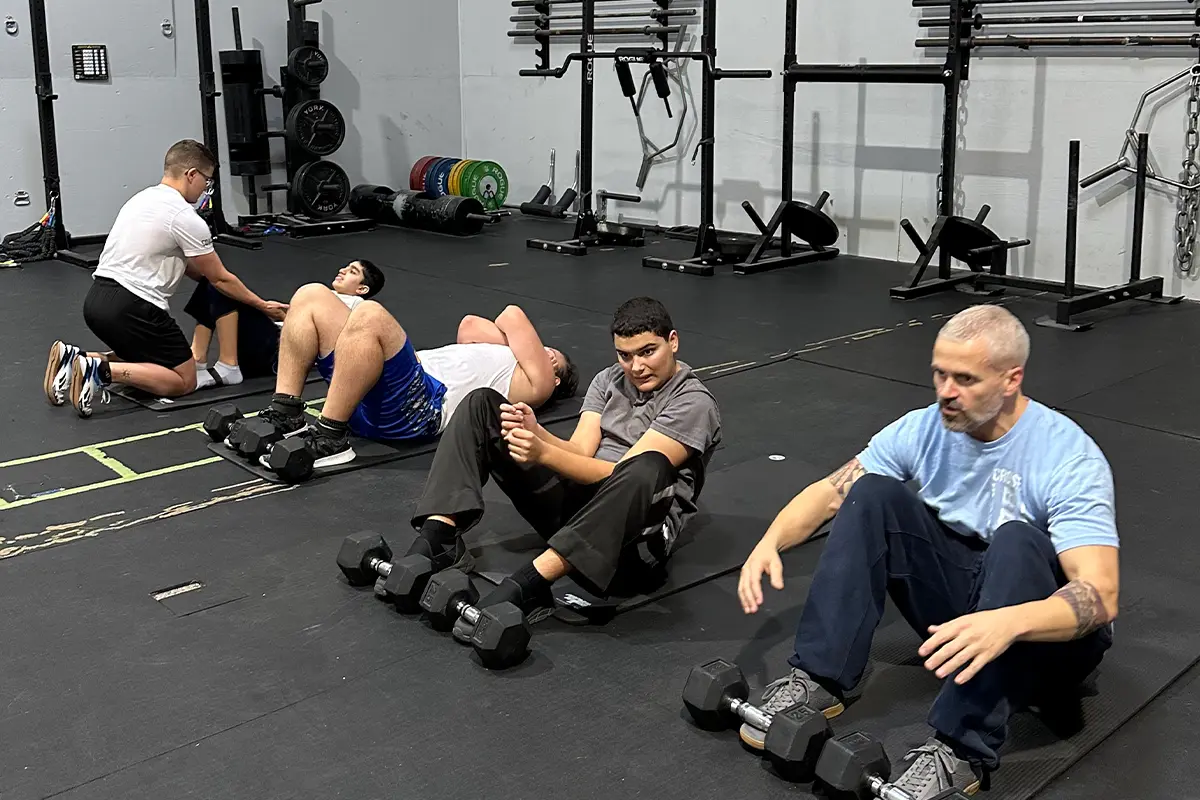 Chad Ciri does sit-ups with weights with participants in a uniquely abled fitness class