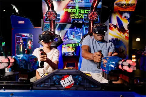 A man and child plat a driving game at a Dave & Busters arcade