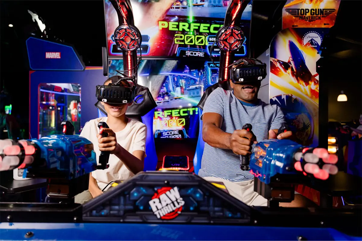 A man and child plat a driving game at a Dave & Busters arcade