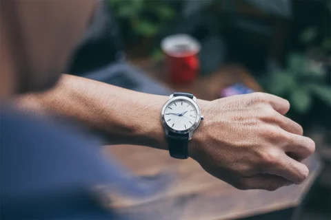 a person looks down at a wrist watch on their hand