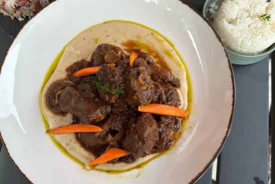 a Dish of meat with carrots and a side of rice at Xaymaca Fusion Kitchen