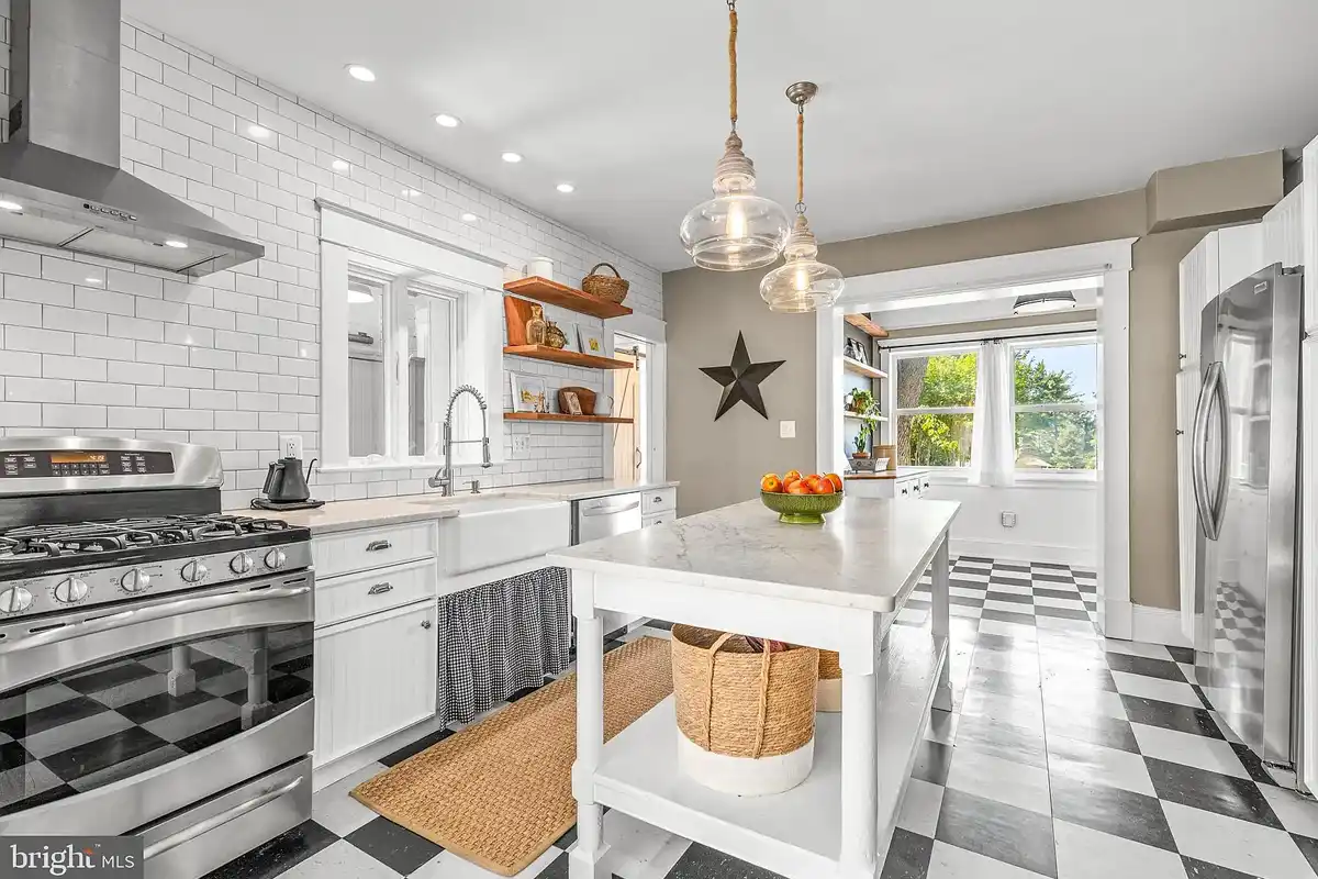 white kitchen with tile accent wall and black-and-white flooring