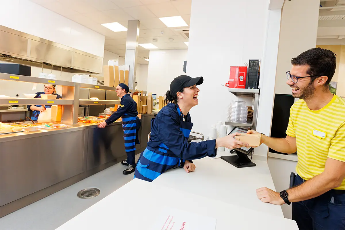 A worker hands food over a counter to a patron at the IKEA restaurant in the UK