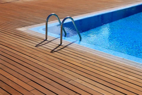 a teak pool deck, pool ladder and water