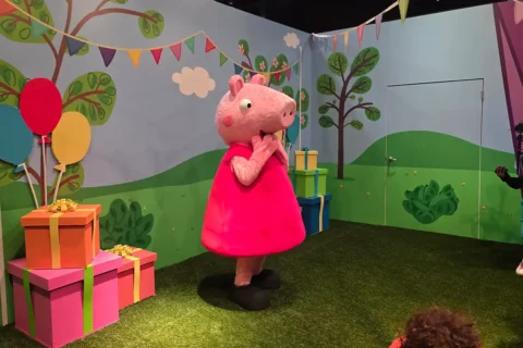 peppa pig standing next to gifts and balloons