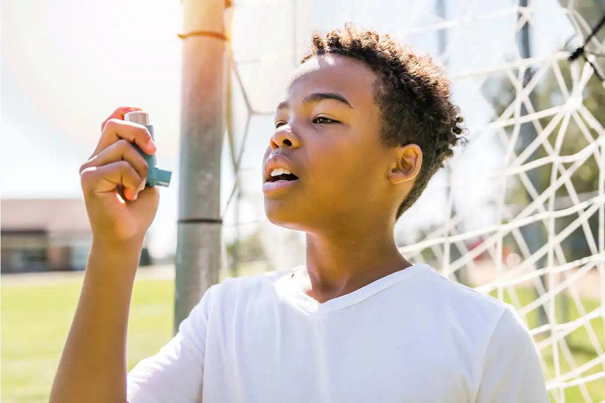 Child with asthma using inhaler outside