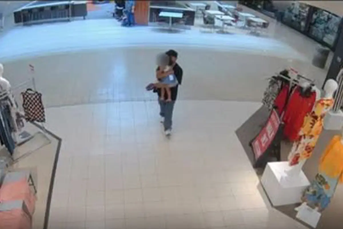 a man holding a young child outside of the play area at Fair Oaks Mall