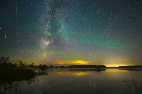 Milky way galaxy and perseid meteor shower. Green glow in the night sky.