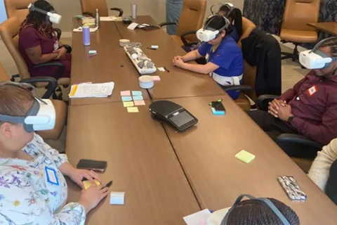 caregivers sit around table wearing virtual reality headsets