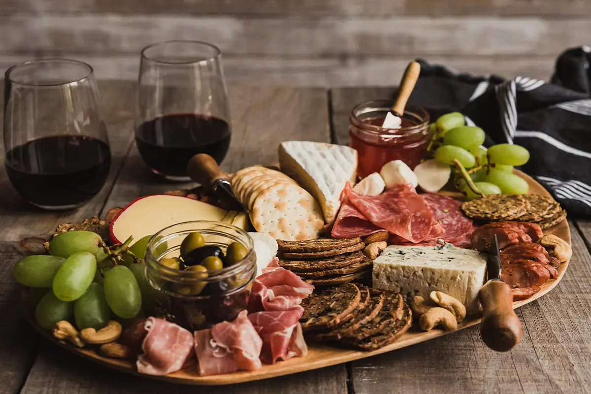 charcuterie tray with crackers, cheese, meats, olives, and grapes