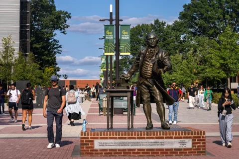 statue of george mason and students walking to and from class