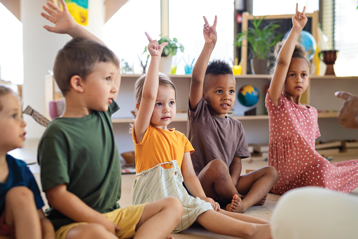 preschool students raising their hands with the number 2