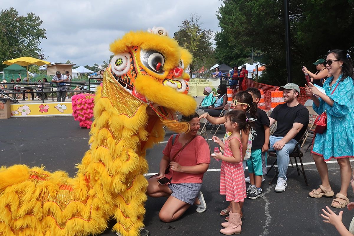 family petting yellow dragon at Taste of Annandale