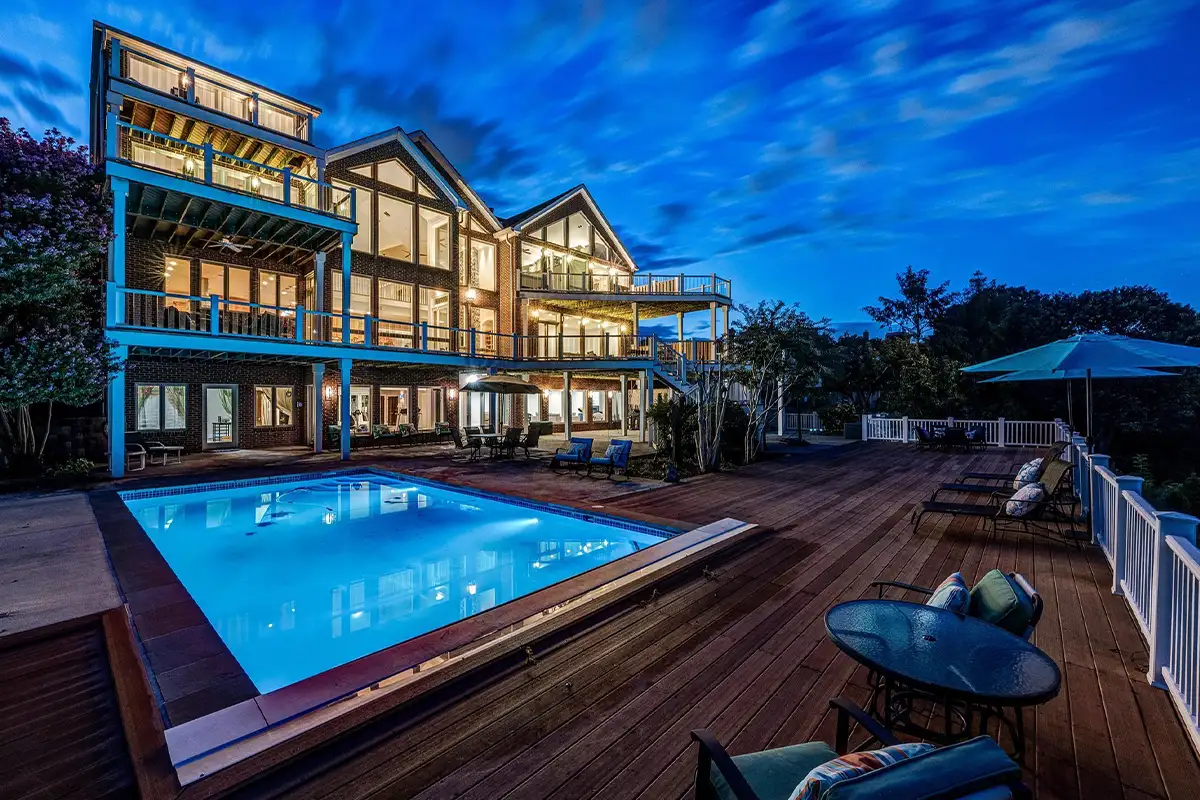 Backyard deck with heated pool and lounge space at night