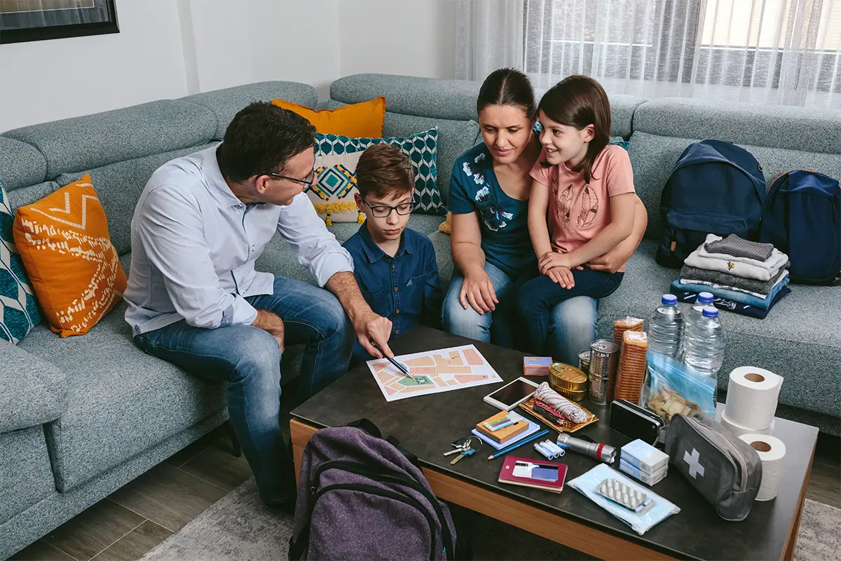 a family looks at a map with emergency supplies on a table