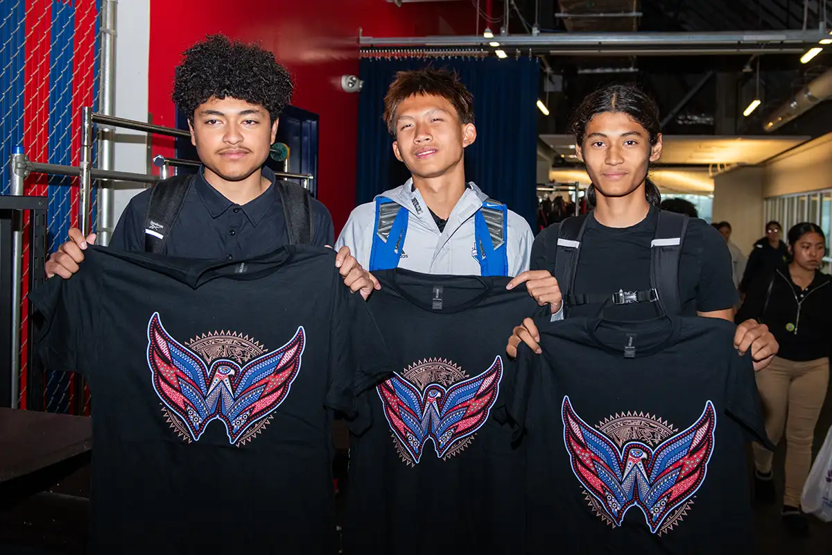 Students holding a specially designed shirt at a Washington Capitals Rink Pass event.