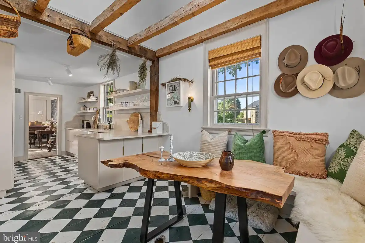 white kitchen with black and white checkered floors and wood beams