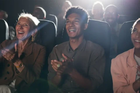 people smiling and clapping watching a movie