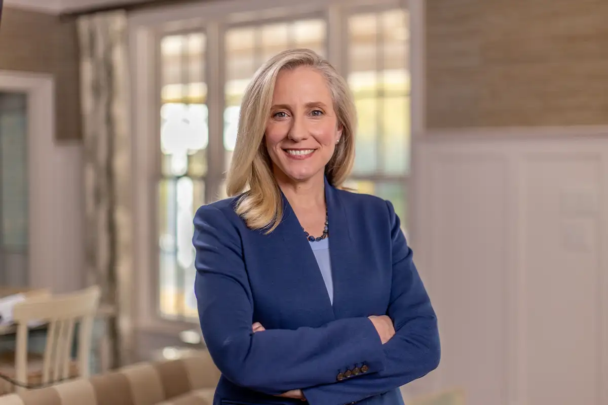 Abigail Spanberger stands smiling with her arms crossed wearing a blue blazer.