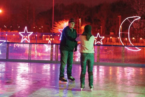Guests ice skating surrounding by holiday light displays at Ice and Lights at Cameron Run Park.