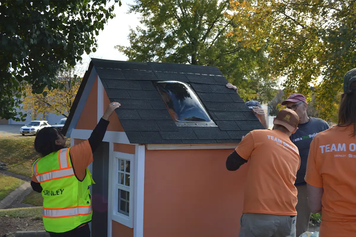 Grunley Construction volunteers installing the skylight to a playhouse. 