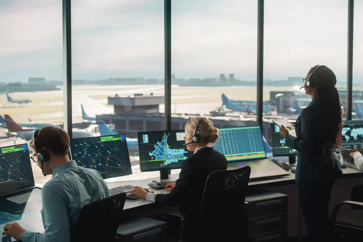 workers sit in front of computer screens in an air traffic control tower at an airport