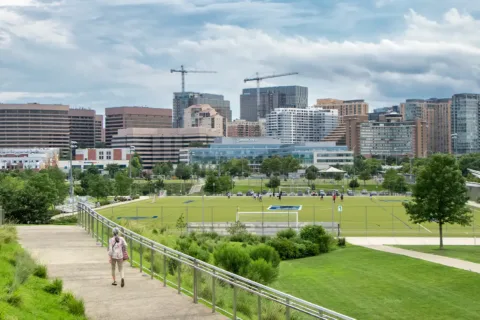 a woman walks on a path with Arlington in the background