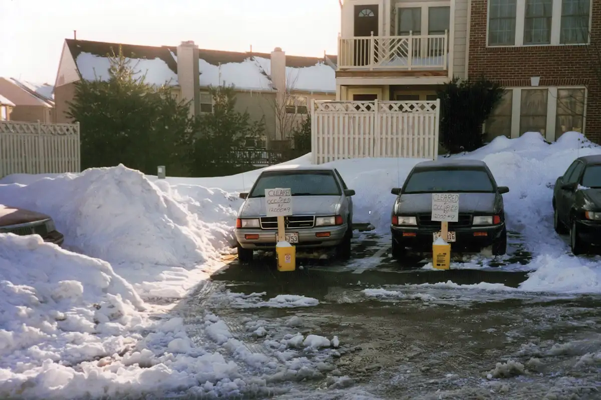 Cars in cleared parking lots during snow storm