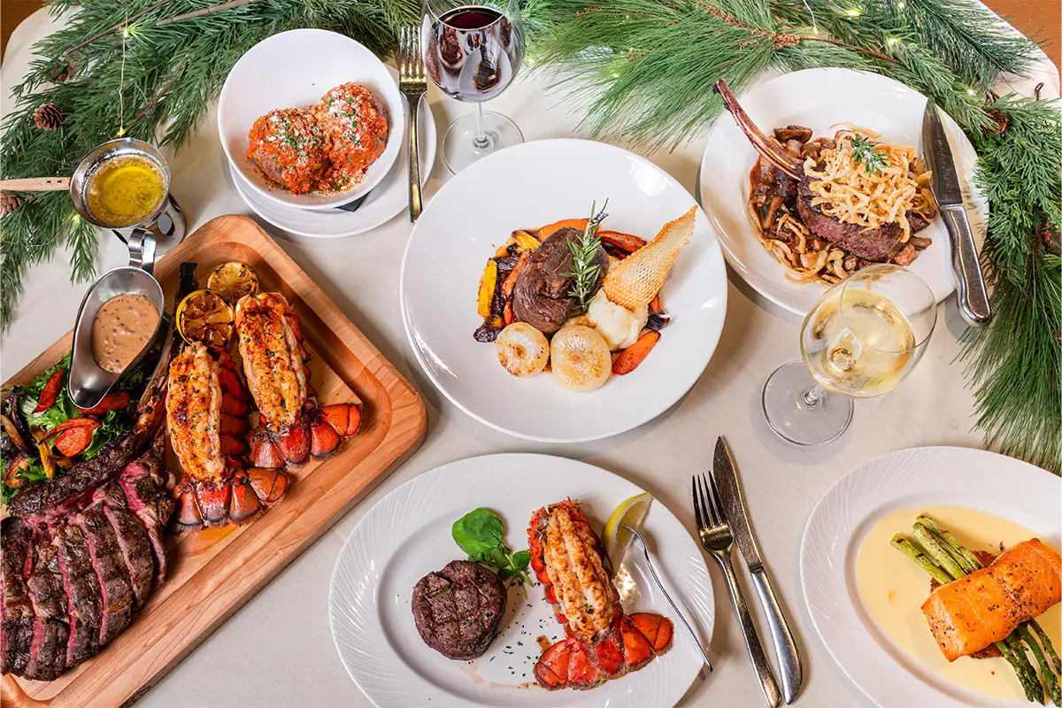 a table decorated with green holiday garland and a variety of dinner dishes