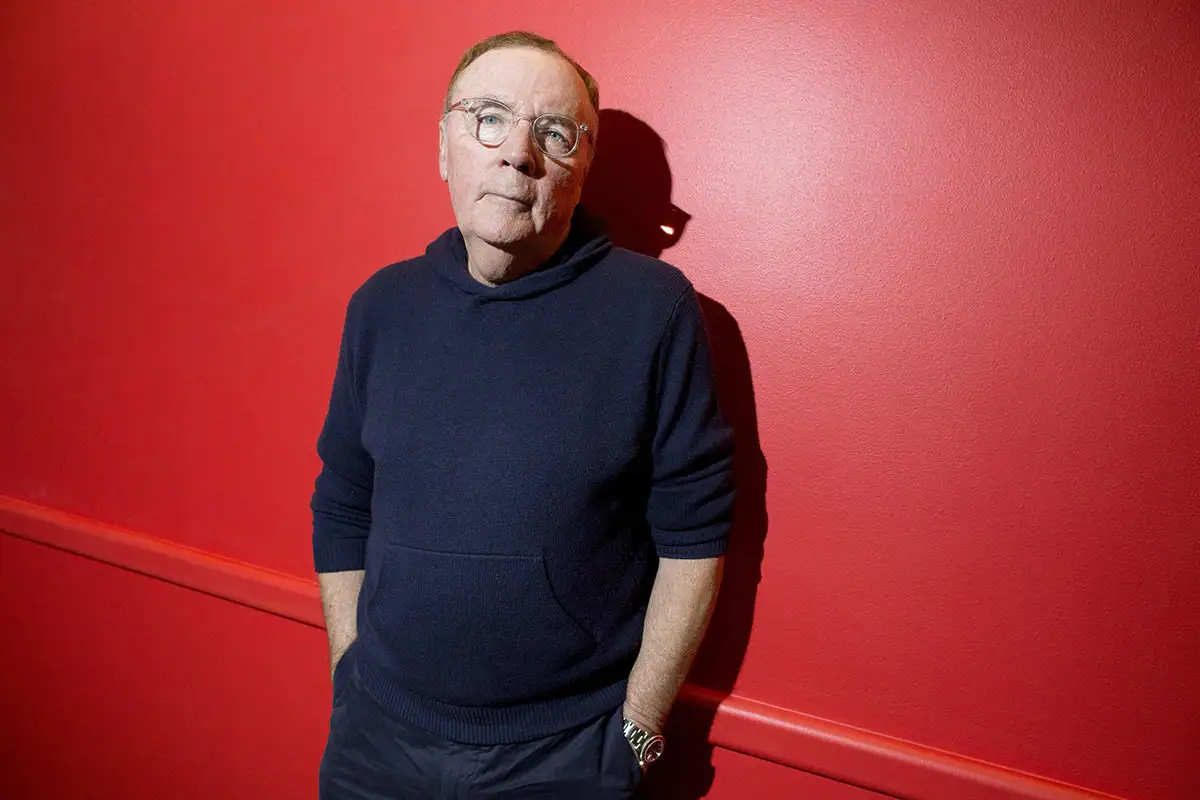 Author James Patterson stands in front of a red background