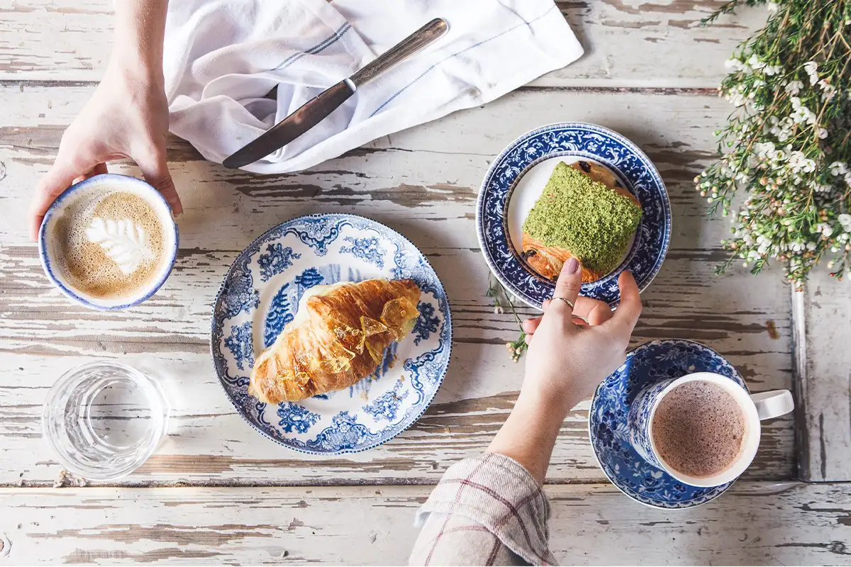 bakery items and coffees on blue plates on a white table