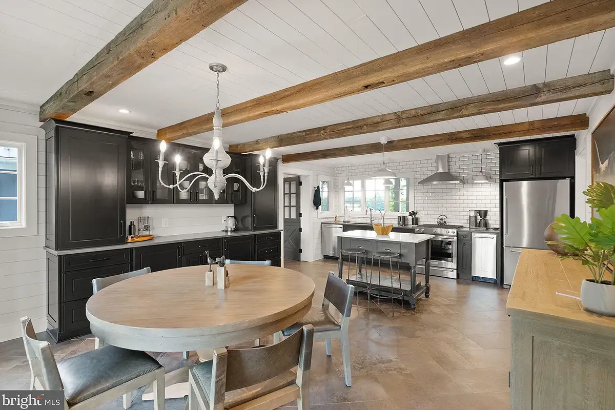 Kitchen area with table, stainless steel appliances, wood beams