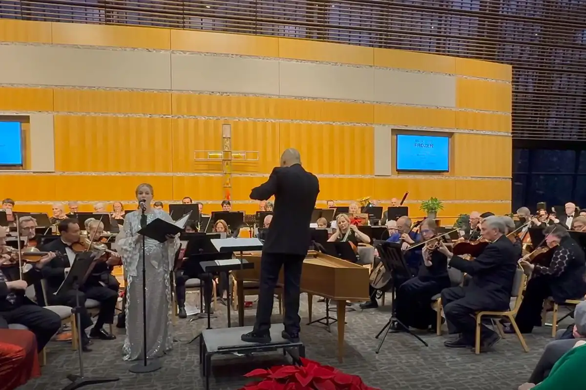 A young girl sings on stage as an orchestra plays at the Winter Delights concert at Reston Community Center
