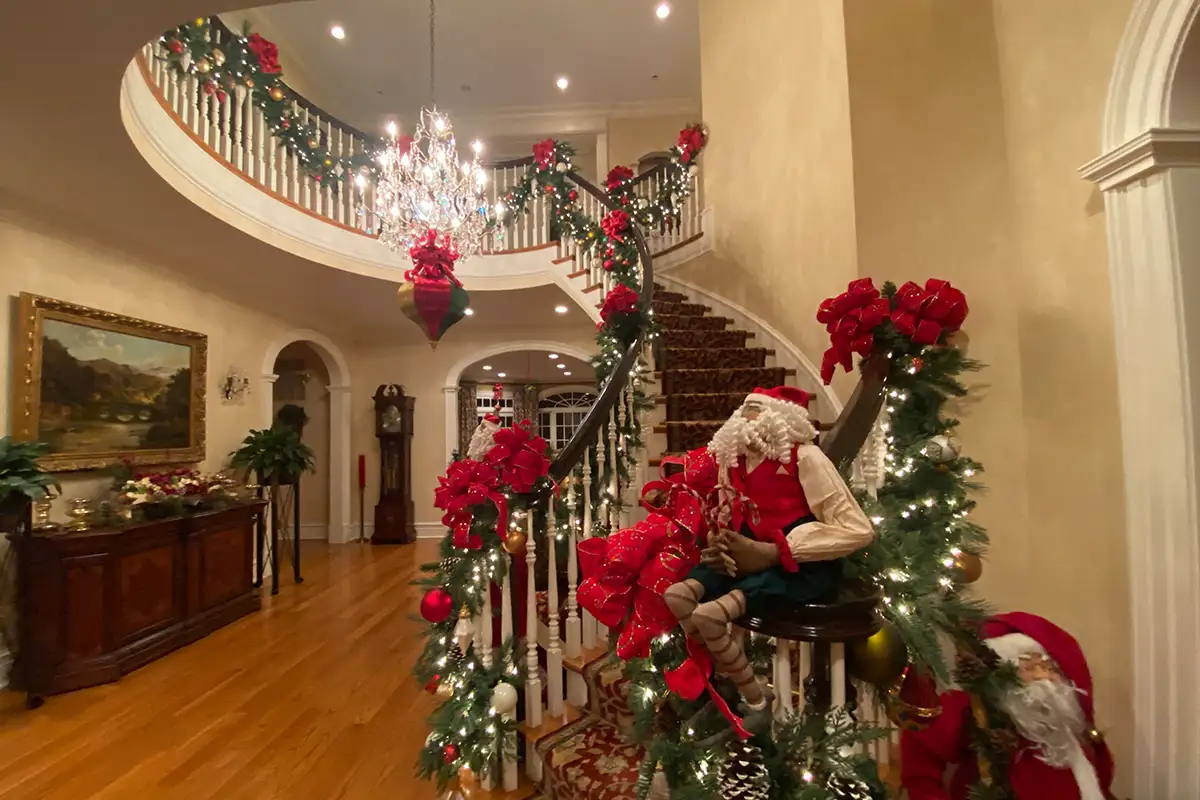 A foyer and stairway banister decorated with holiday garland and ribbon