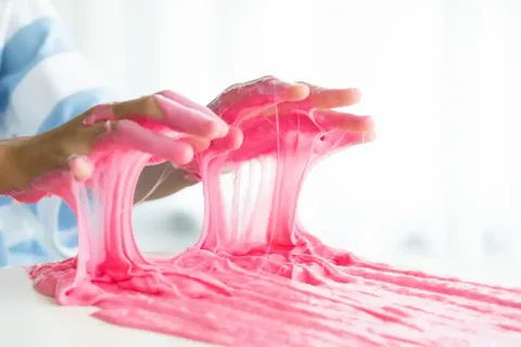 person with pink slime on hands
