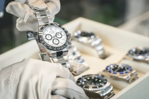 a person with gloves holds a Rolex watch