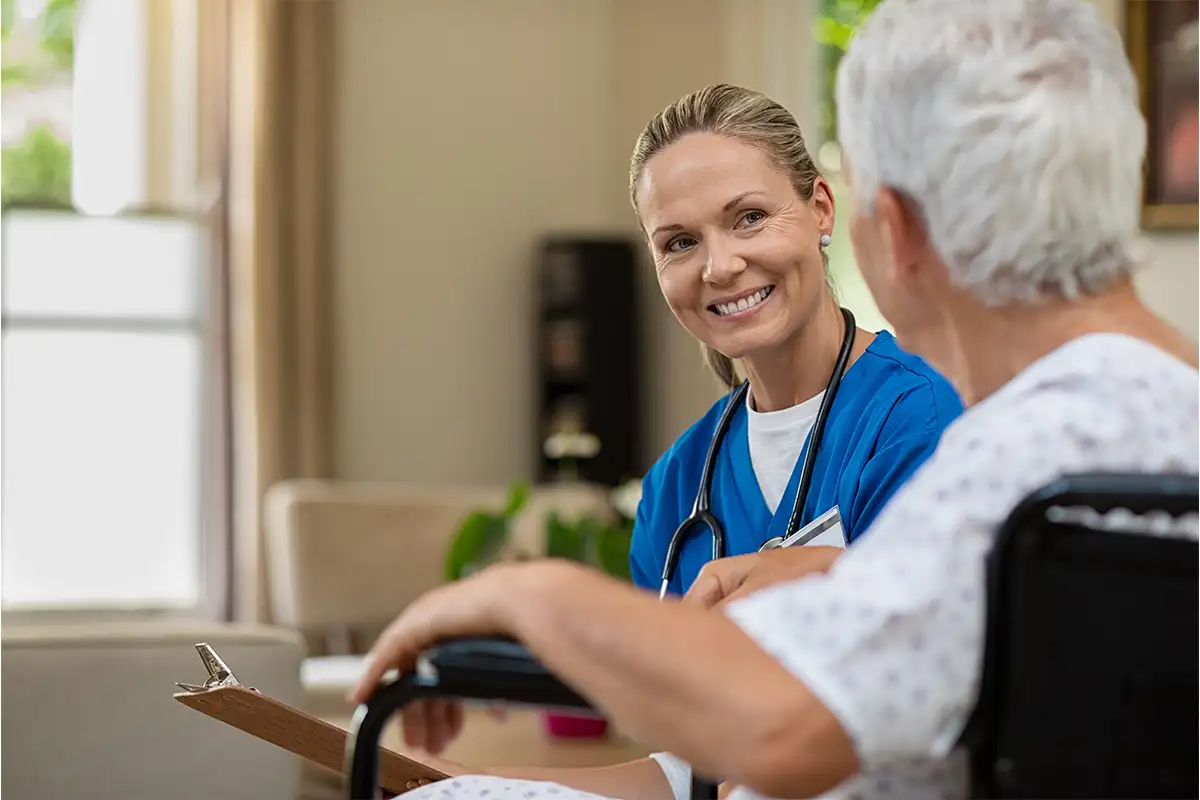 a nurse speaks with an elderly person in a wheelchair