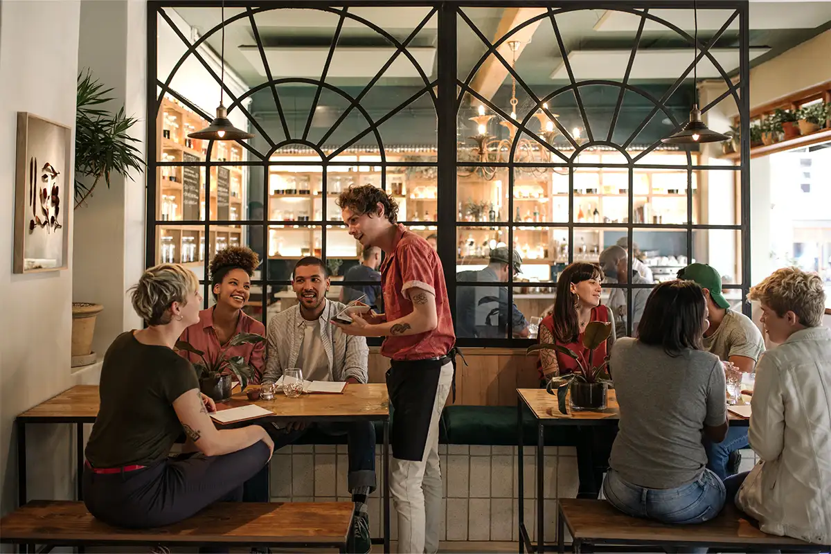 a waiter speaks to a group of people eating at a restaurant