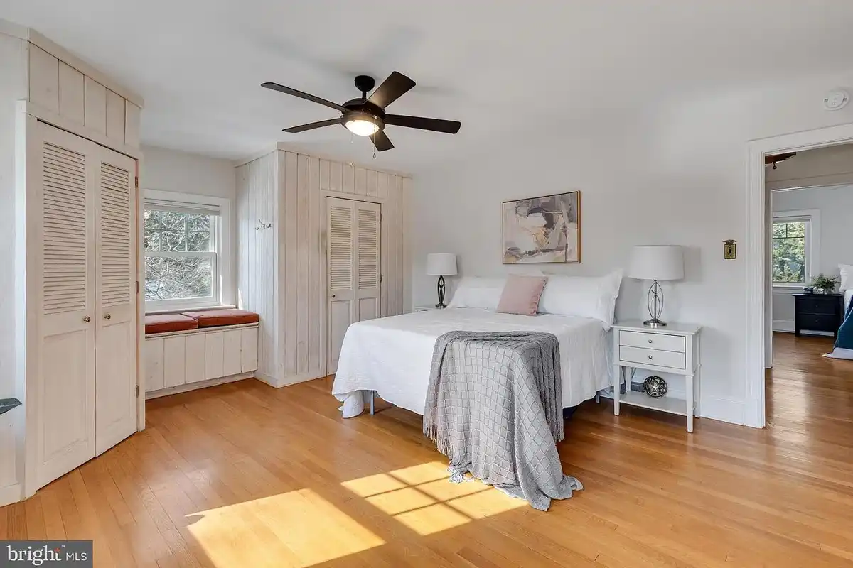 primary bedroom with bench seat and hardwood floors