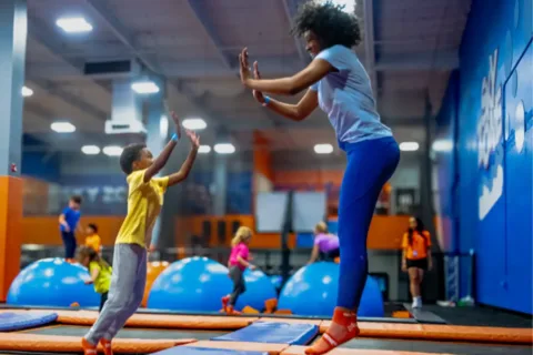a woman and child high five each other while jumping on a trampoline