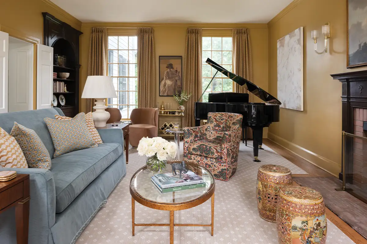 The living room’s walls are saturated in Sherwin-Williams Mannered Gold. The sofa is by Taylor King, with a Samuel & Sons Greek key tape detail.