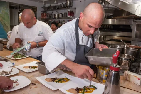 Chef Jonathan and Chef Brandon Dearden plating food in a kitchen