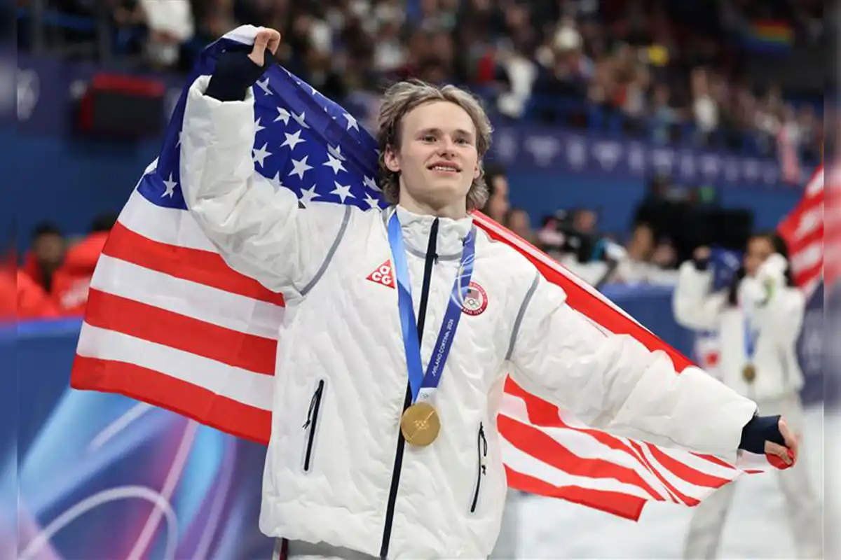 Ilia malinin skating with gold medal and flag at 2026 Olympics