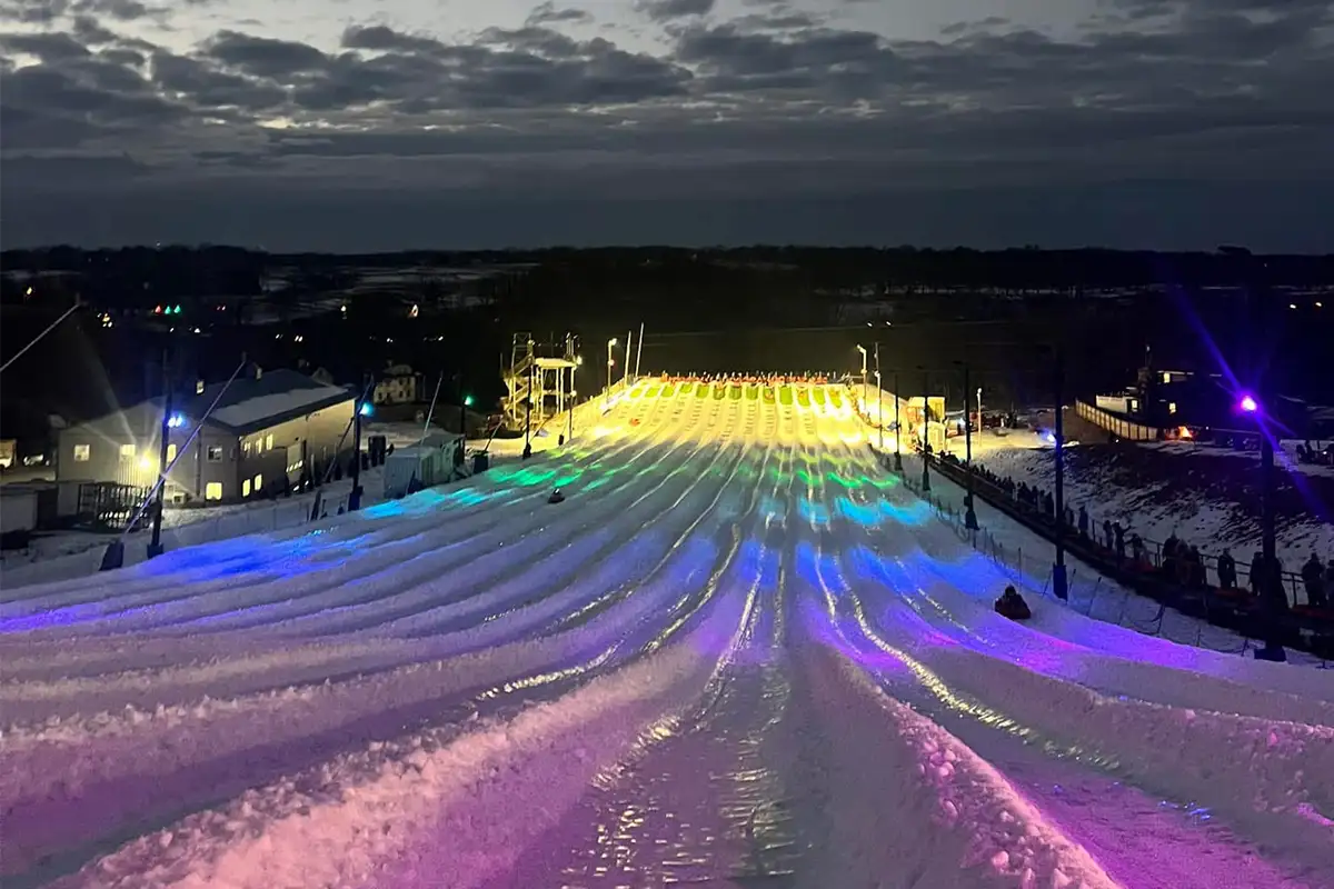 a snow tubing hill lit up with colorful lights at night