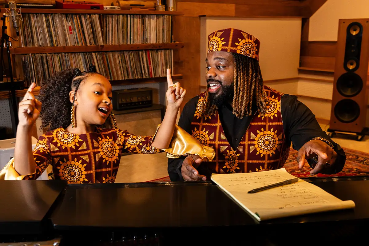 Aura V and her father sing at a piano